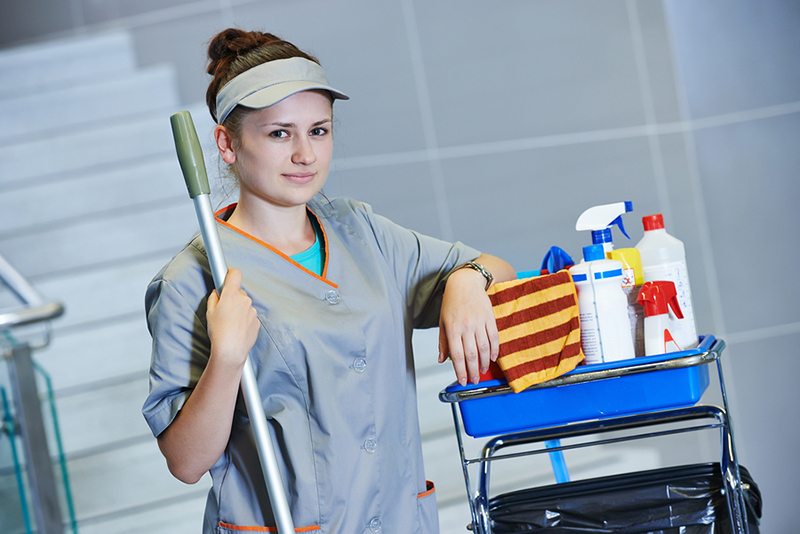 portrait of female cleaner in uniform with mop and cleaning equipment